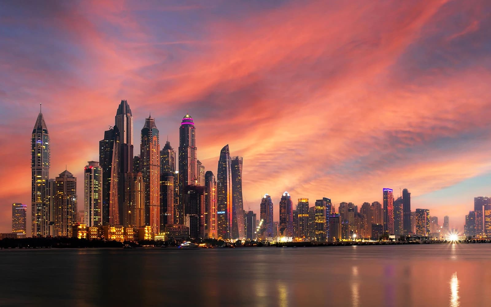 Gün batımında Dubai Marina silueti; aydınlanmış gökdelenler ve suya vuran yansımalar