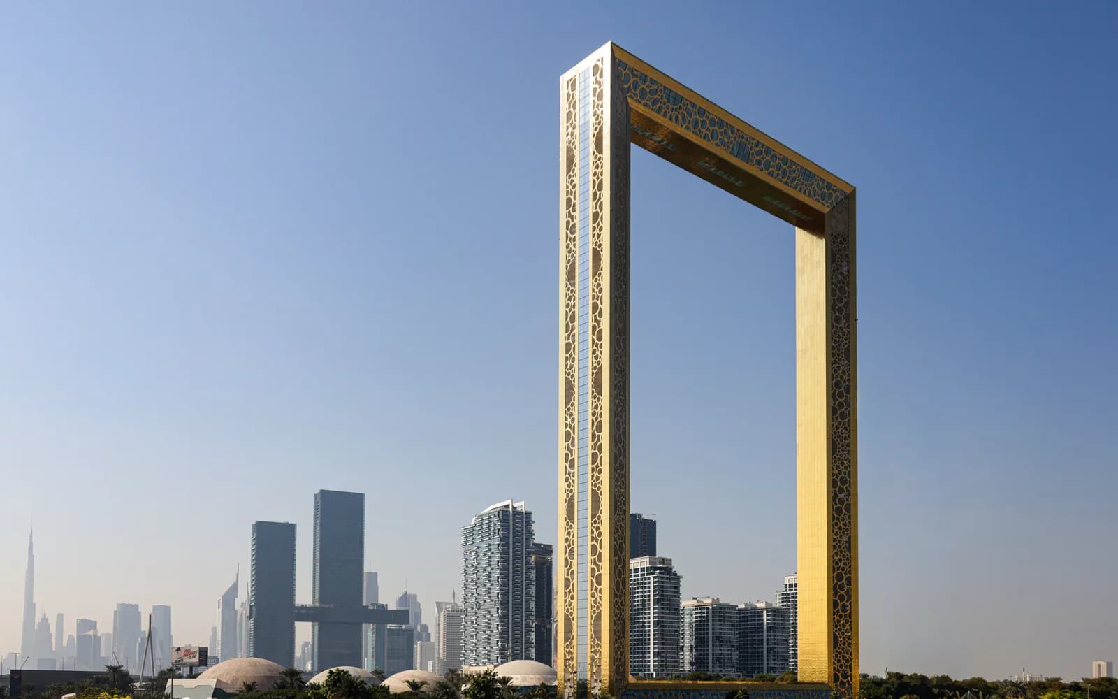 Dubai Frame'in altın rengi çerçeve yapısının tamamı ve arkasında Downtown Dubai silueti